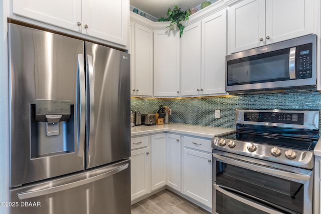 kitchen featuring white cabinetry, appliances with stainless steel finishes, light stone counters, and decorative backsplash