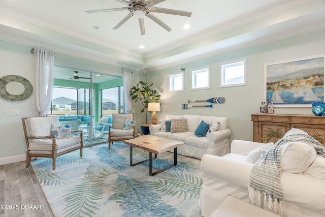 living room featuring a tray ceiling, crown molding, and ceiling fan