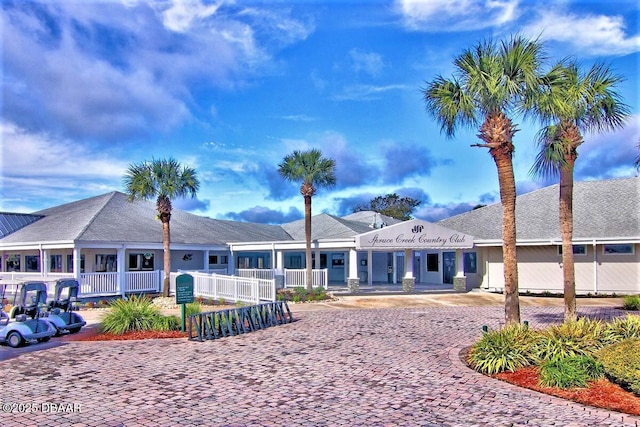 rear view of property featuring decorative driveway and fence