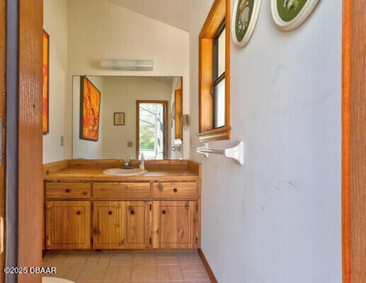 bathroom with vanity, baseboards, and vaulted ceiling