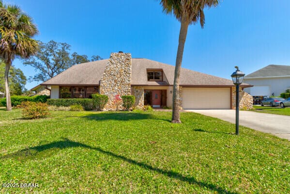 view of front facade with a front yard, an attached garage, and driveway