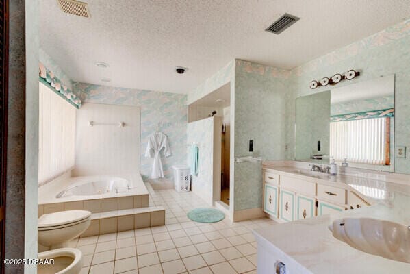 full bath featuring visible vents, a garden tub, a textured ceiling, a bidet, and wallpapered walls