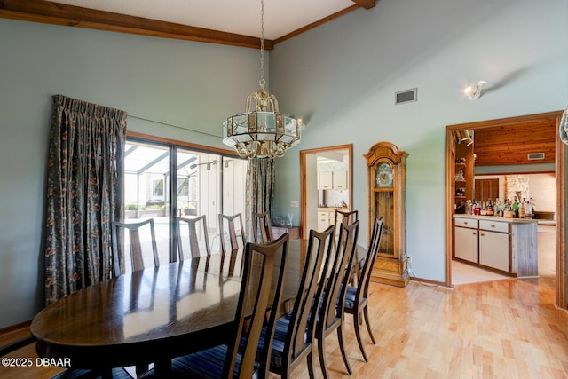 dining space featuring visible vents, high vaulted ceiling, a notable chandelier, and light wood finished floors