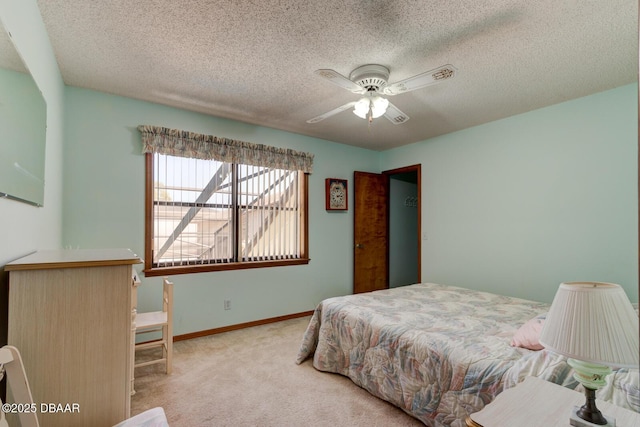 carpeted bedroom with ceiling fan, baseboards, and a textured ceiling