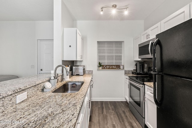 kitchen featuring light stone counters, a sink, white cabinets, appliances with stainless steel finishes, and dark wood-style floors