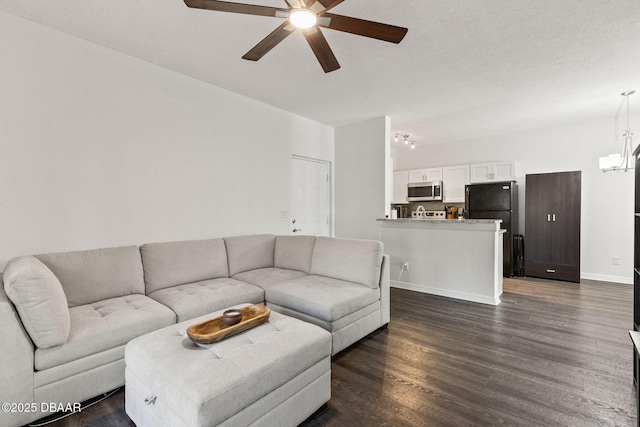 living room featuring a textured ceiling, baseboards, dark wood-type flooring, and ceiling fan with notable chandelier