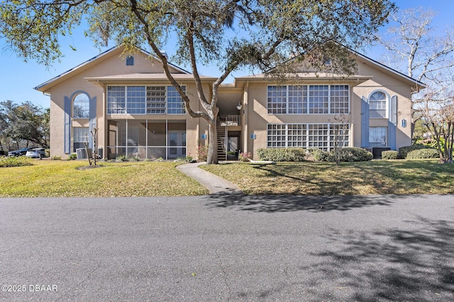 view of front of house with stairs, a front lawn, and stucco siding