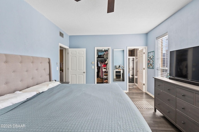 bedroom featuring dark wood finished floors, a closet, visible vents, a spacious closet, and a textured ceiling