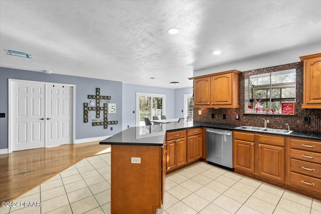 kitchen with a sink, a peninsula, backsplash, and dishwasher