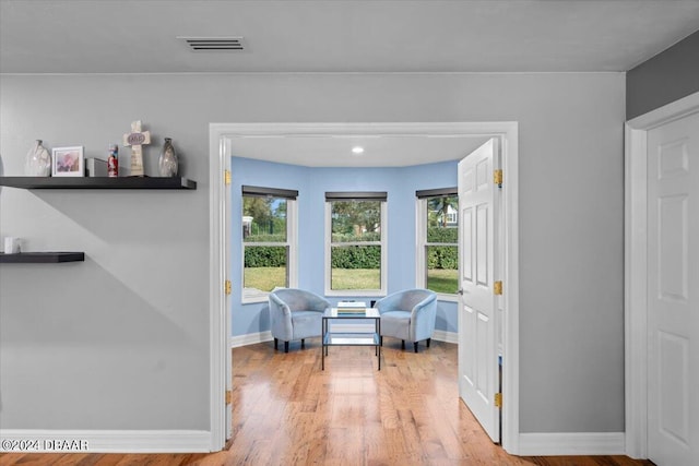 living area featuring baseboards, plenty of natural light, visible vents, and wood finished floors