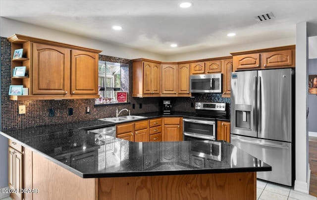 kitchen with tasteful backsplash, visible vents, appliances with stainless steel finishes, a peninsula, and a sink