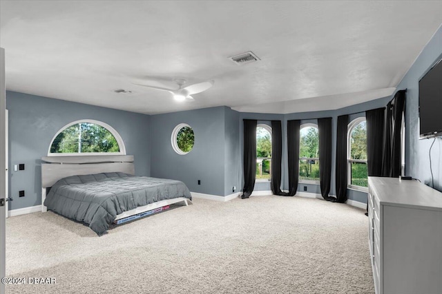 bedroom with light colored carpet, ceiling fan, visible vents, and baseboards