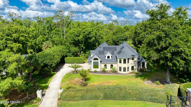 view of front of house featuring dirt driveway, solar panels, a front lawn, and fence