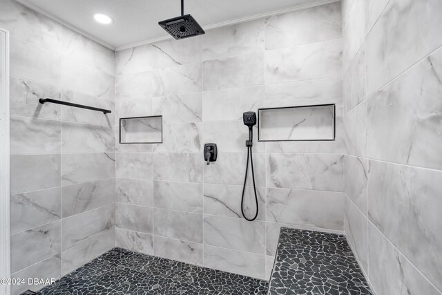 bathroom featuring crown molding and a tile shower