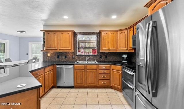 kitchen featuring stainless steel appliances, brown cabinetry, a peninsula, and a sink