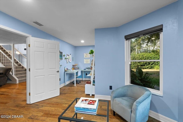 living area featuring stairs, wood finished floors, visible vents, and baseboards