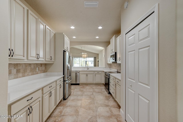 kitchen featuring lofted ceiling, sink, tasteful backsplash, decorative light fixtures, and stainless steel appliances