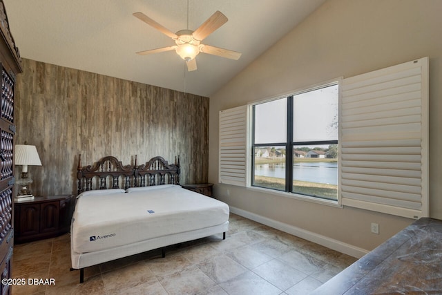 bedroom featuring a water view, high vaulted ceiling, ceiling fan, and wood walls