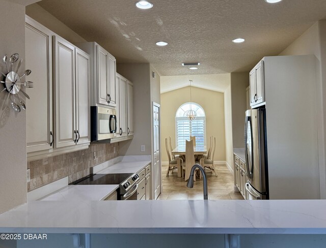 kitchen featuring pendant lighting, sink, light stone countertops, vaulted ceiling, and stainless steel dishwasher