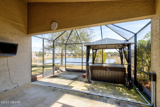 view of patio / terrace with a lanai, a hot tub, and a water view