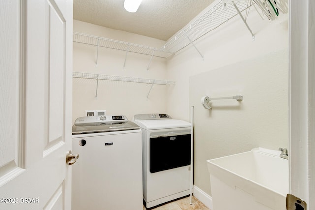 laundry area with separate washer and dryer, sink, and a textured ceiling