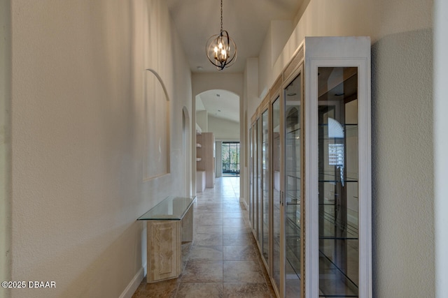 corridor with vaulted ceiling and an inviting chandelier