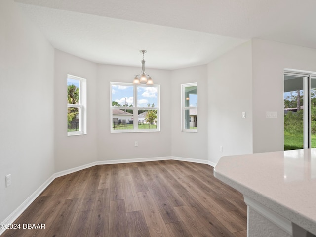 unfurnished dining area with dark wood-type flooring and a notable chandelier