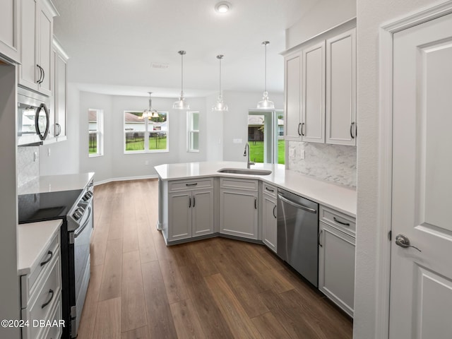 kitchen featuring stainless steel appliances, dark hardwood / wood-style floors, sink, and decorative light fixtures