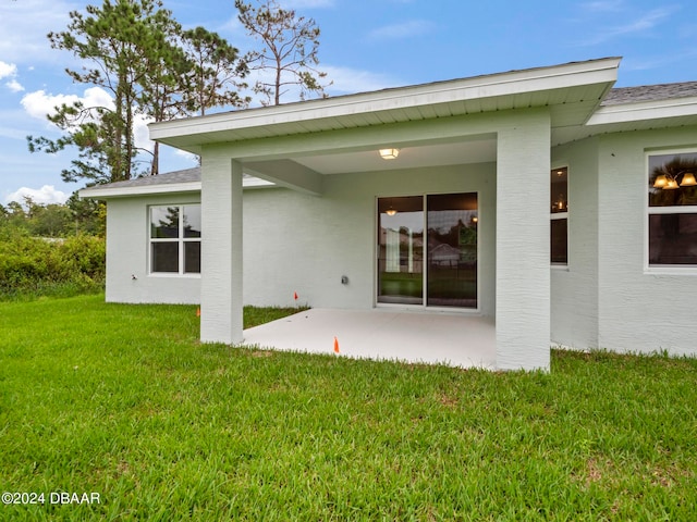 back of property featuring a patio and a yard