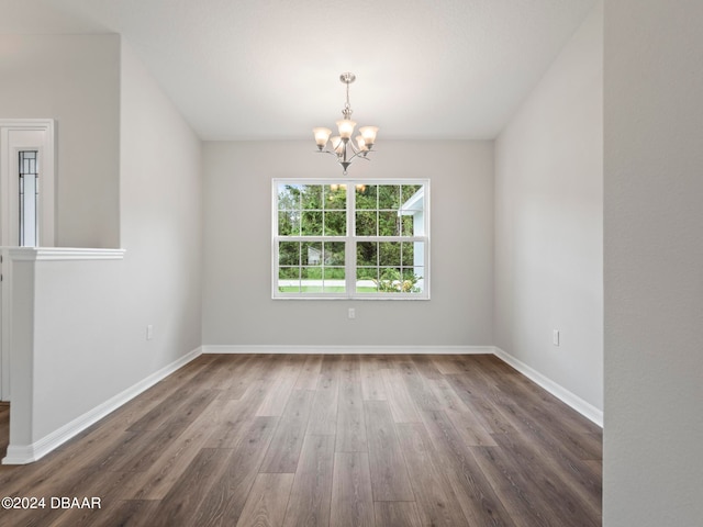 spare room featuring dark hardwood / wood-style flooring and a chandelier