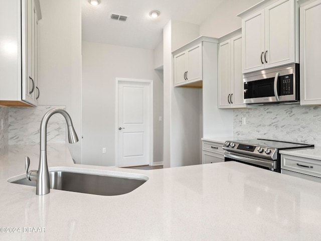 kitchen featuring white cabinets, decorative backsplash, stainless steel appliances, and sink