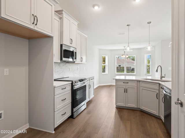 kitchen featuring dark wood-type flooring, pendant lighting, tasteful backsplash, white cabinetry, and appliances with stainless steel finishes