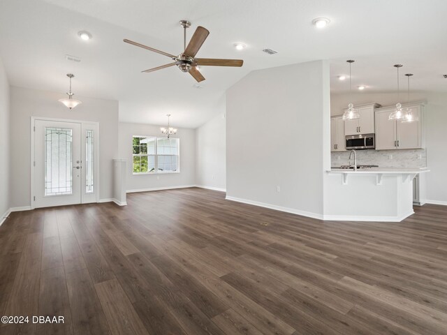 unfurnished living room featuring sink, vaulted ceiling, dark hardwood / wood-style floors, and ceiling fan with notable chandelier