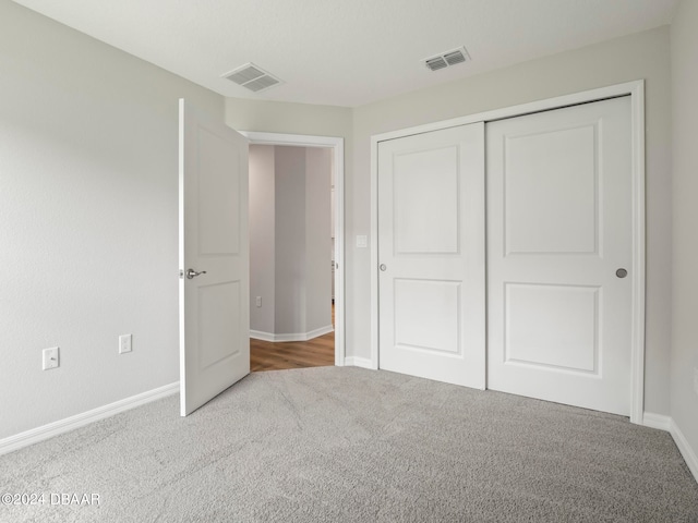 unfurnished bedroom with light colored carpet and a closet