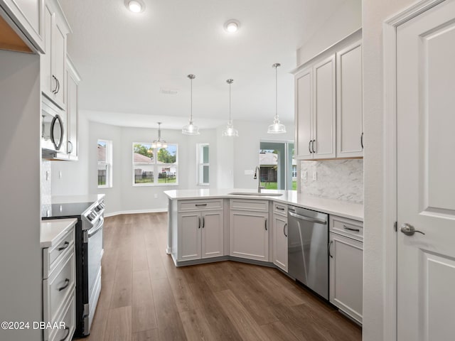 kitchen with dark hardwood / wood-style flooring, stainless steel appliances, white cabinets, sink, and pendant lighting