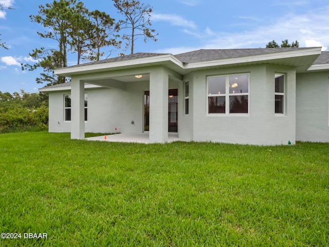 back of house featuring a patio area and a lawn