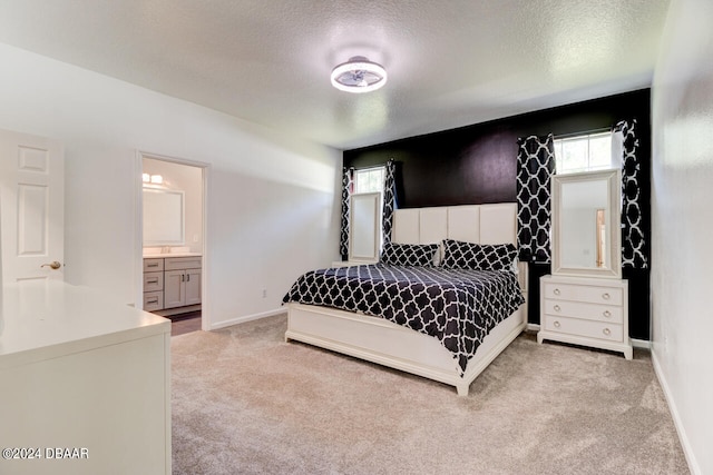 bedroom with multiple windows, a textured ceiling, light colored carpet, and ensuite bathroom