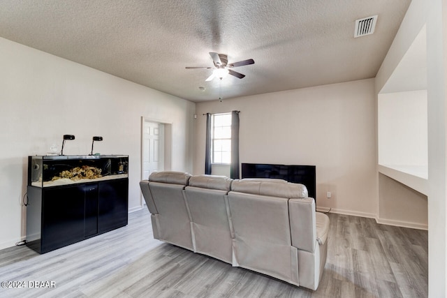 living room with light hardwood / wood-style floors, ceiling fan, and a textured ceiling