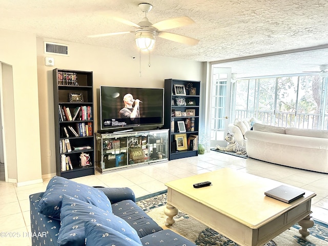 living room featuring ceiling fan, light tile patterned floors, and a textured ceiling