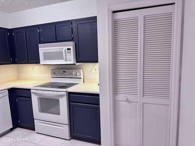 kitchen featuring a textured ceiling, light tile patterned flooring, and white appliances