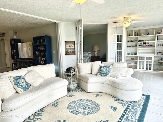 living room featuring ceiling fan, light tile patterned flooring, and a textured ceiling