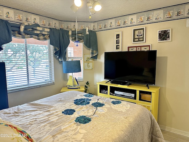 bedroom with hardwood / wood-style floors, ceiling fan, and a textured ceiling