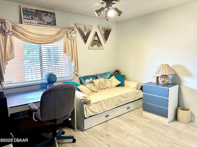 bedroom featuring ceiling fan, a textured ceiling, and light wood-type flooring