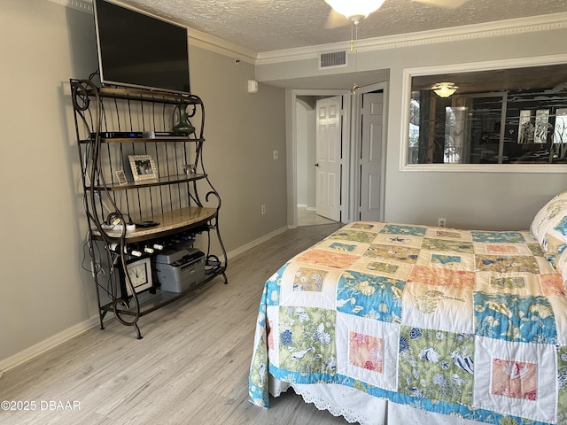 bedroom featuring a textured ceiling, hardwood / wood-style flooring, ceiling fan, and ornamental molding