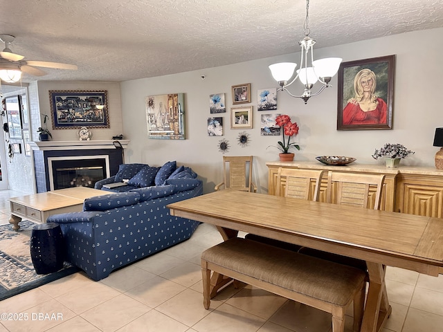 tiled dining space featuring ceiling fan with notable chandelier and a textured ceiling