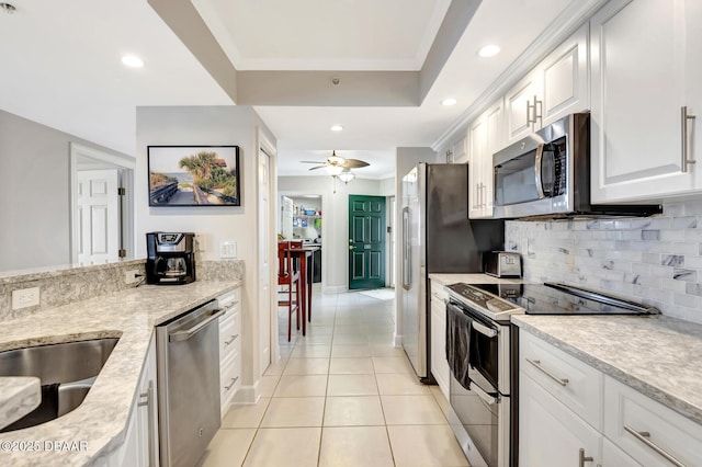 kitchen featuring white cabinets, appliances with stainless steel finishes, backsplash, ceiling fan, and light tile patterned floors