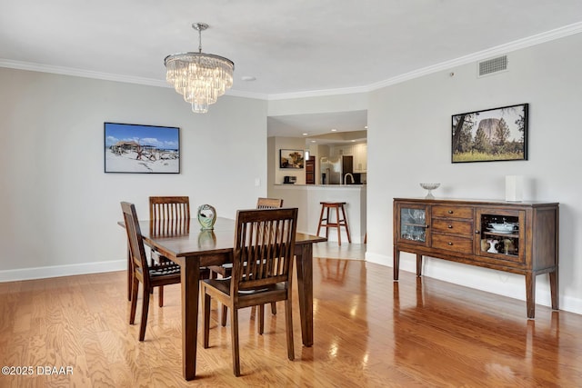 dining space featuring a chandelier, light hardwood / wood-style flooring, and ornamental molding