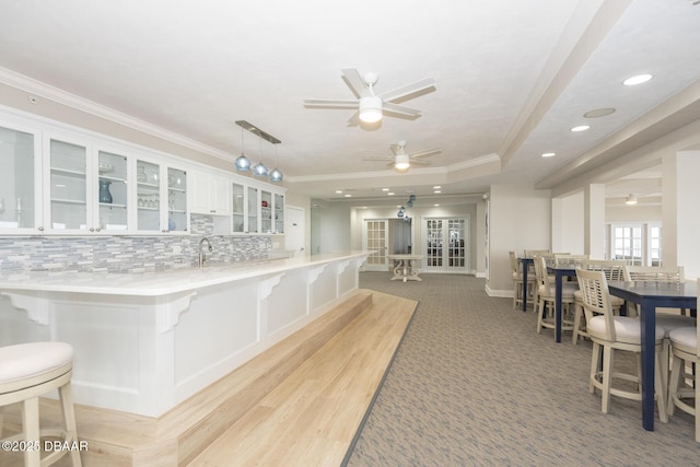 kitchen featuring a kitchen breakfast bar, white cabinets, pendant lighting, and ornamental molding