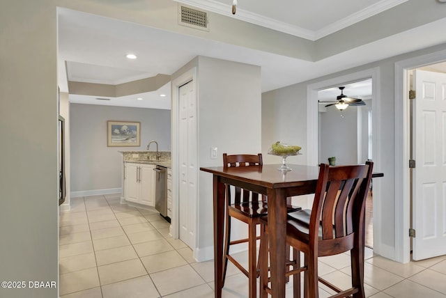 tiled dining space featuring ceiling fan, sink, and crown molding