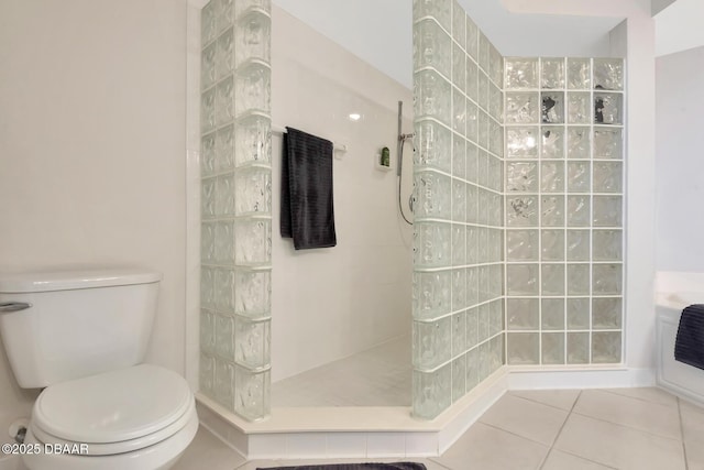 bathroom featuring a tile shower, toilet, and tile patterned flooring